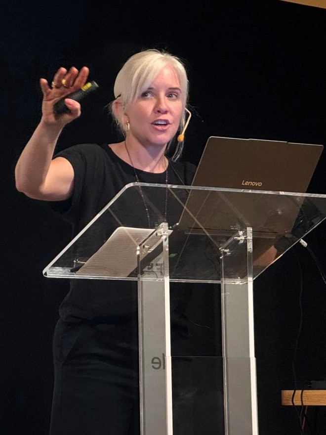 Brooke Gallagher presenting at Nationale Opera & Ballet, holding a slide clicker as she addresses the marketing and communications team.